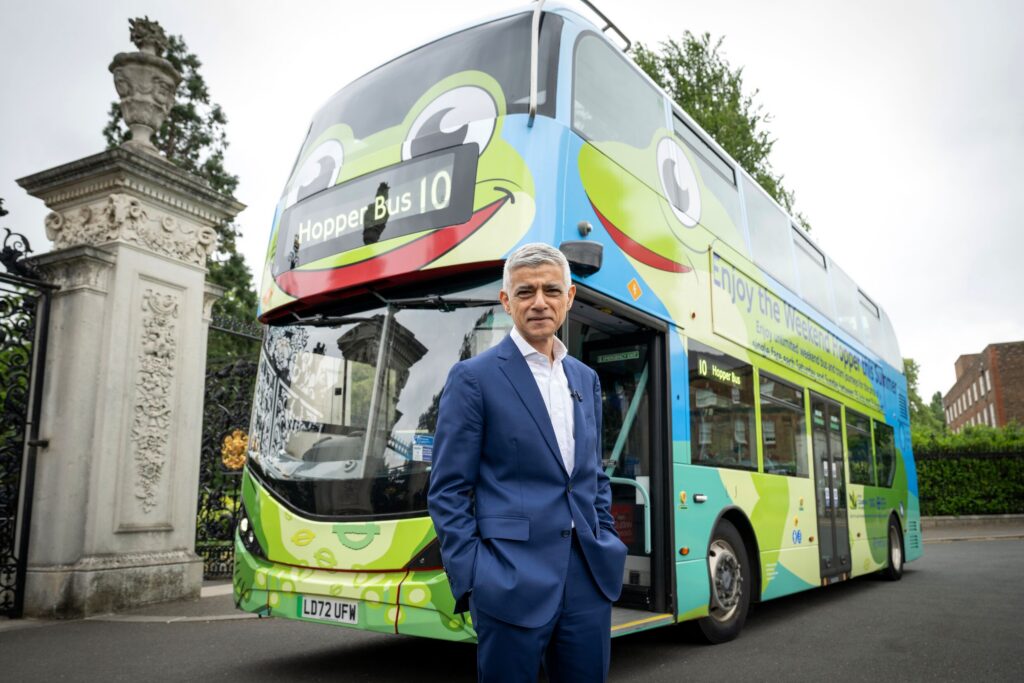 Sadiq Khan stands in front of a big green London bus that's designed to look like a frog.