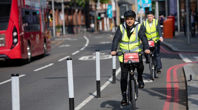 Sadiq cycles through London wearing a high-vis yellow jacket.